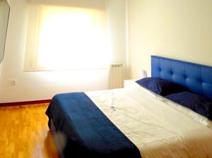 1 dormitorio con 1 cama con cabecero azul y ventana en 5 bedrooms villa with city view private pool and jacuzzi at Porto en Oporto