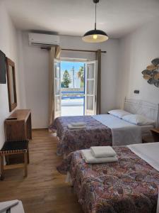 a hotel room with three beds and a balcony at Hotel Kastelakia Mykonos in Mýkonos City