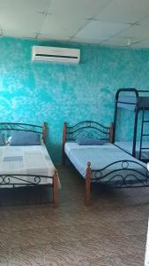 2 Betten in einem Zimmer mit blauer Wand in der Unterkunft Rancho Juancho in Portobelo