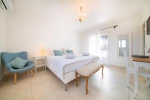 ein weißes Schlafzimmer mit einem Bett und einem blauen Stuhl in der Unterkunft Les Capucines Saint Tropez in Saint-Tropez