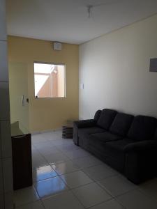 a living room with a black couch and a window at Hospedagem Petrolina in Petrolina