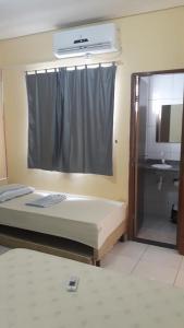 een slaapkamer met een bed, een wastafel en een spiegel bij Hospedagem Petrolina in Petrolina