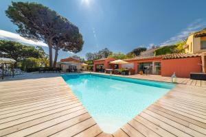 a swimming pool with a wooden deck and a house at Les Capucines Saint Tropez in Saint-Tropez