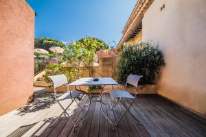 einen Tisch und Stühle auf einer Holzterrasse in der Unterkunft Les Capucines Saint Tropez in Saint-Tropez