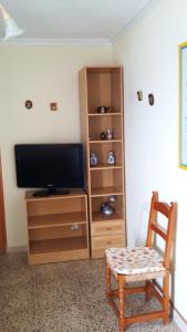 a room with a tv and a chair and a cabinet at 2 bedrooms apartement with sea view shared pool and furnished balcony at Aguilas in Águilas