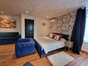 1 dormitorio con 1 cama y 1 silla azul en LE MANOIR- CLUNY, en Cluny