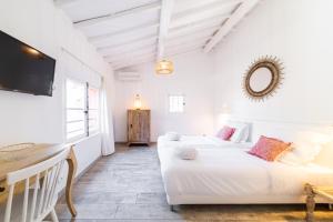 ein weißes Zimmer mit 2 Betten und einem Tisch in der Unterkunft Les Capucines Saint Tropez in Saint-Tropez