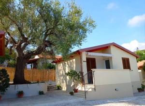 una casa con un árbol y una valla en Case vacanze la Quercia en Marina di Camerota
