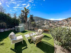a garden with chairs and a table on the grass at Villa Palmire, large terrace with jacuzzi available in La Turbie