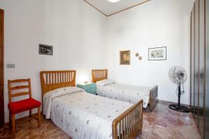 two beds in a room with a fan and a chair at 4 bedrooms apartement with furnished terrace and wifi at Cava de' Tirreni 3 km away from the beach in Cava deʼ Tirreni