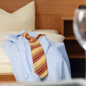 une chemise blanche et une cravate assise sur un lit dans l'établissement Akzent Hotel Residence Bautzen, à Bautzen