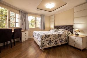 1 dormitorio con 1 cama, escritorio y ventanas en Garmisch 302 - My Home Temporada, en Gramado