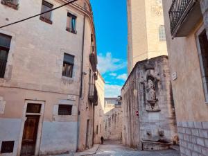an alley between two buildings with a statue in the middle at Cathedral Dreams in Girona