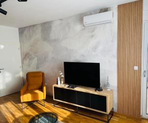 a living room with a television and a chair at Platinum_Luxury_Apartment in Teslić