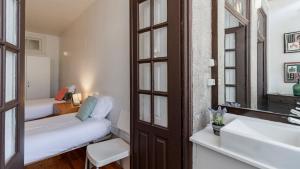 y baño con cama, lavabo y espejo. en Porto 61 - Bright 2BR w/ Balcony by LovelyStay, en Oporto