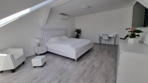 a white bedroom with a bed and a staircase at Bécsi Kapu Apartman in Vác