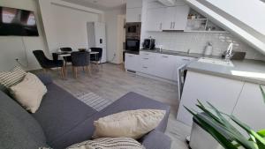 ein Wohnzimmer und eine Küche mit einem Sofa und einem Tisch in der Unterkunft Bécsi Kapu Apartman in Vác