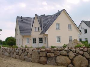 uma casa atrás de uma parede de pedra em Urlaubsglück Familien- & Hunde-Paradies em Rankwitz