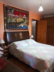 a bedroom with a bed and a painting on the wall at Hospedagem na cidade das flores in Pareci Novo