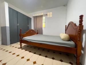 ein Schlafzimmer mit einem Holzbett in einem Zimmer in der Unterkunft Résidence Sapotille in Matoury