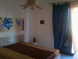a bedroom with a bed with blue curtains and a window at SASSI E MARE in Policoro