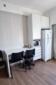 a kitchen with a desk with two chairs and a refrigerator at Flat R Borges Lagoa Ibirapuera c/ garagem UH1005 in Sao Paulo