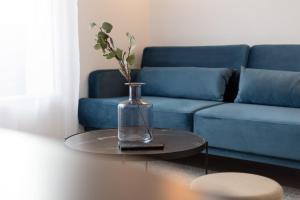 un sofá azul y un jarrón de cristal sobre una mesa en The Blue and Gold Cocoon Appart hotel en Viry-Châtillon