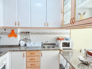 a kitchen with white cabinets and a sink at Apartamento Florida EME in Sanxenxo +3 photos