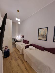 Cette chambre comprend deux lits, une table et une télévision. dans l'établissement A casa di Marisa, à Rome
