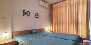 1 dormitorio con cama azul y ventana grande en Elit 4 Apartments, en Sunny Beach