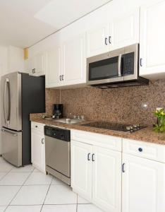 a kitchen with white cabinets and a stainless steel refrigerator at Studio with shared pool furnished balcony and wifi at Lowlands in Lowlands