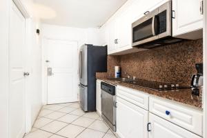 a kitchen with white cabinets and a stainless steel refrigerator at Elegant Studio in Lowlands - 55 sqm - Pool in Lowlands