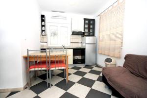 een keuken met een geblokte vloer met een tafel en een koelkast bij Cosy Apartment in Žrnovo - 30 sqm with Shared Pool in Korčula