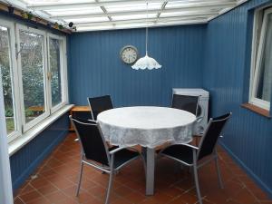 a dining room with a table and chairs and a clock at Haus Katharina in Loissin
