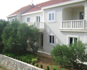 een wit huis met een hek ervoor bij Cosy Apartment in Žrnovo - 30 sqm with Shared Pool in Korčula +5 foto's