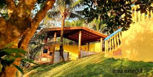 a yellow house with a wooden roof on top of it at Suíte em casa particular Sidi & Val - Soul Almada - Praia da Almada Ubatuba in Ubatuba