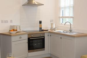 kuchnia z białymi szafkami, umywalką i oknem w obiekcie Pike O'Blisco w mieście Bowness-on-Windermere