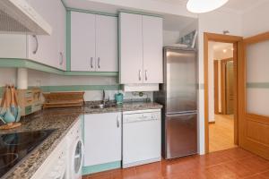 una cucina con armadietti bianchi e frigorifero di Bluebol, apartamento a 2 km de Llanes a Llanes