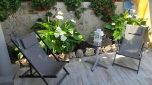 a patio with two chairs and a table and flowers at Cactus house relax in Corchiano