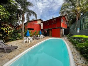 a swimming pool with chairs and umbrellas next to a house at Casa a 3 min andando da Praia de Paúba com WIFI top in São Sebastião