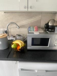a kitchen counter with a microwave and a bowl of fruit at Boutique apartment in Wicklow
