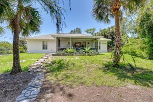 a white house with palm trees in the yard at Pet-Friendly Naples Vacation Rental with Fire Pit! in Naples