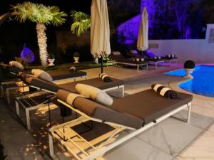 eine Reihe von Chaiselongues neben einem Pool in der Unterkunft Villa Santo in Babići