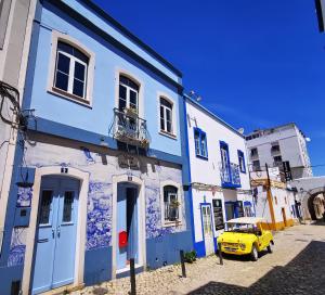 um carro amarelo estacionado em frente a um edifício azul em Charming Portuguese style apartment, for rent "Vida à Portuguesa", "Gaivota" Alojamento Local em Portimão