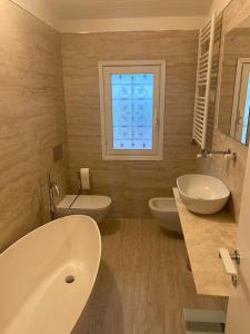 un bagno con due lavandini, una vasca e una finestra di Terrazza sulle Isole Design&View a Stresa