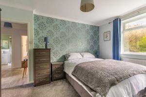 a bedroom with a bed and a dresser and a window at Church Close in Coltishall