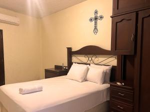 een slaapkamer met een bed met een kruis aan de muur bij Hotel Quinta Maya in Flores