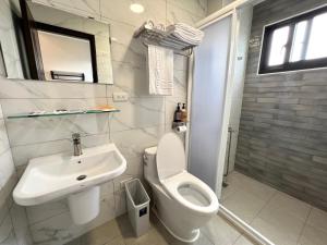 ein weißes Bad mit einem Waschbecken und einem WC in der Unterkunft Mandarin Fish Homestay in Magong