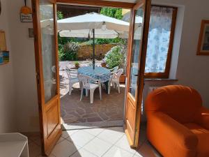 una porta aperta su un patio con tavolo e ombrellone di Appartamento nel parco a Marciana