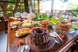 una mesa con muchos tipos diferentes de pasteles y tartas en Pousada Bicho Preguiça, en Pipa